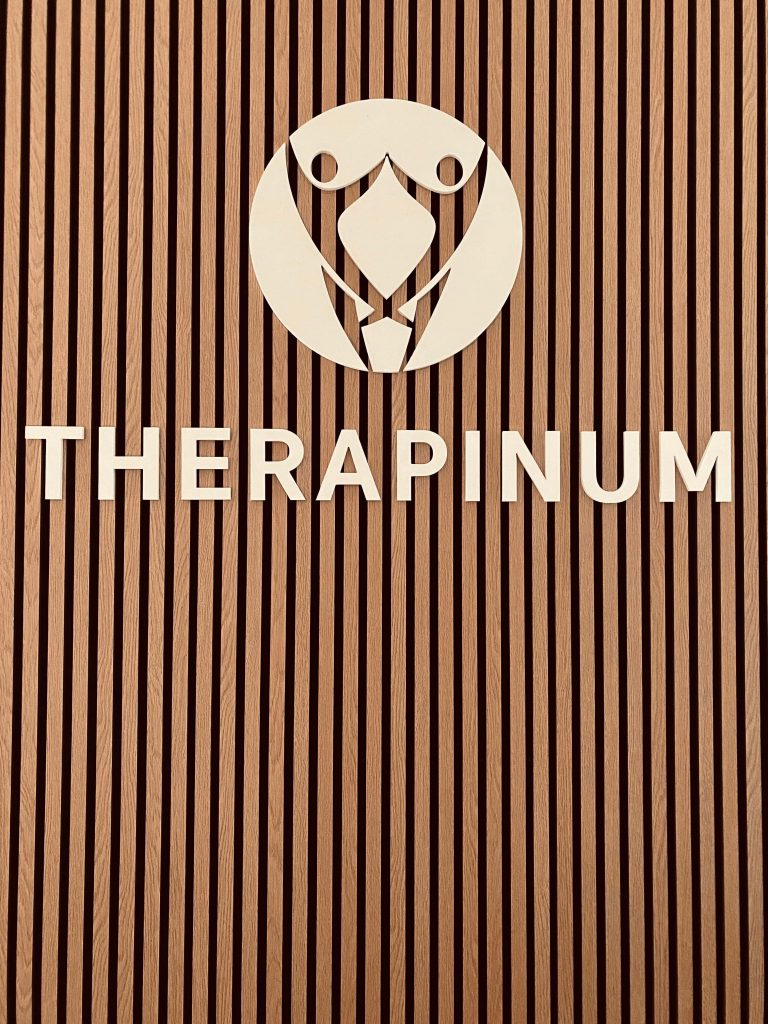 eine Tafel mit dem Logo und Namen von therapinum im Büroflur von therapinum