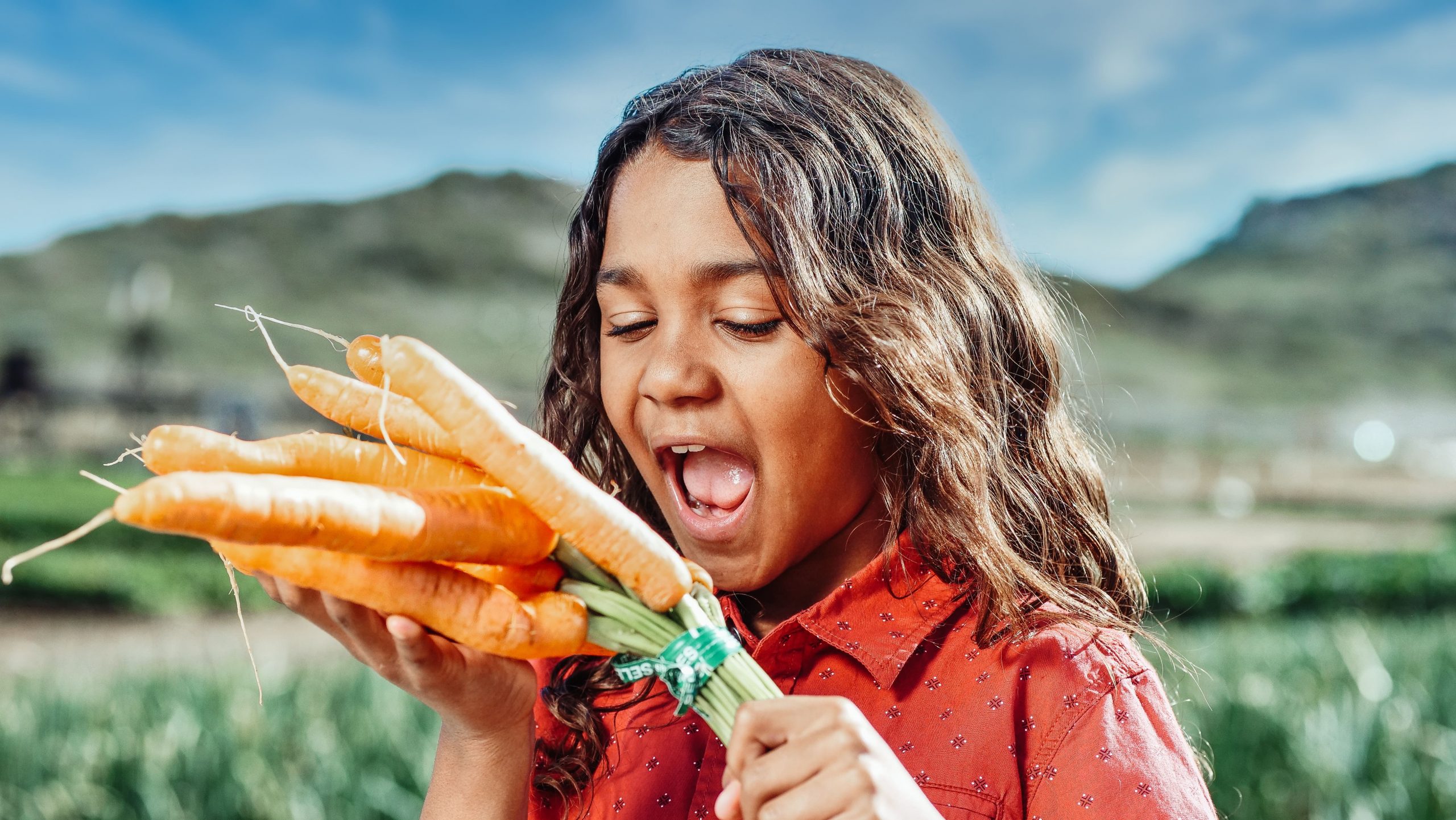 das Bild eines kleinen Mädchens, das spielerisch Karotten essen möchte, gesunde Gewohnheiten sind etwas, das therapinum vermitteln möchte